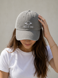 A woman wearing a light gray EMBROIDERED CAP with a white embroidered design of a ringed planet and the text 'I NEED MY SPACE'.